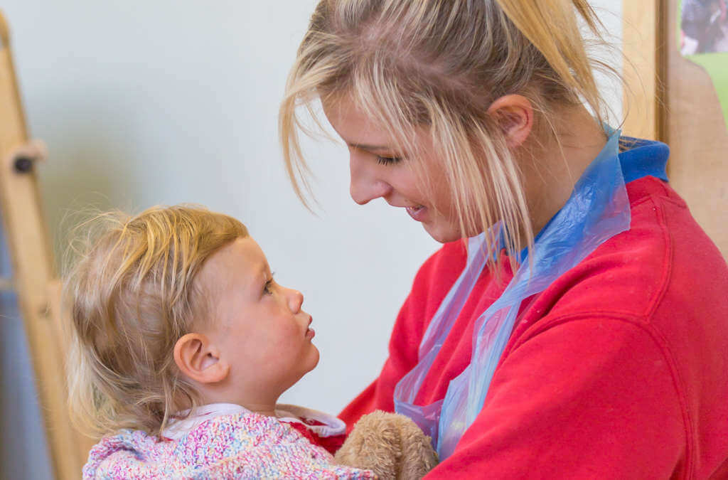 Child being cared for b nursery staff member